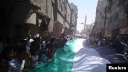 Demonstrators hold a giant flag as they march through the streets of Damascus