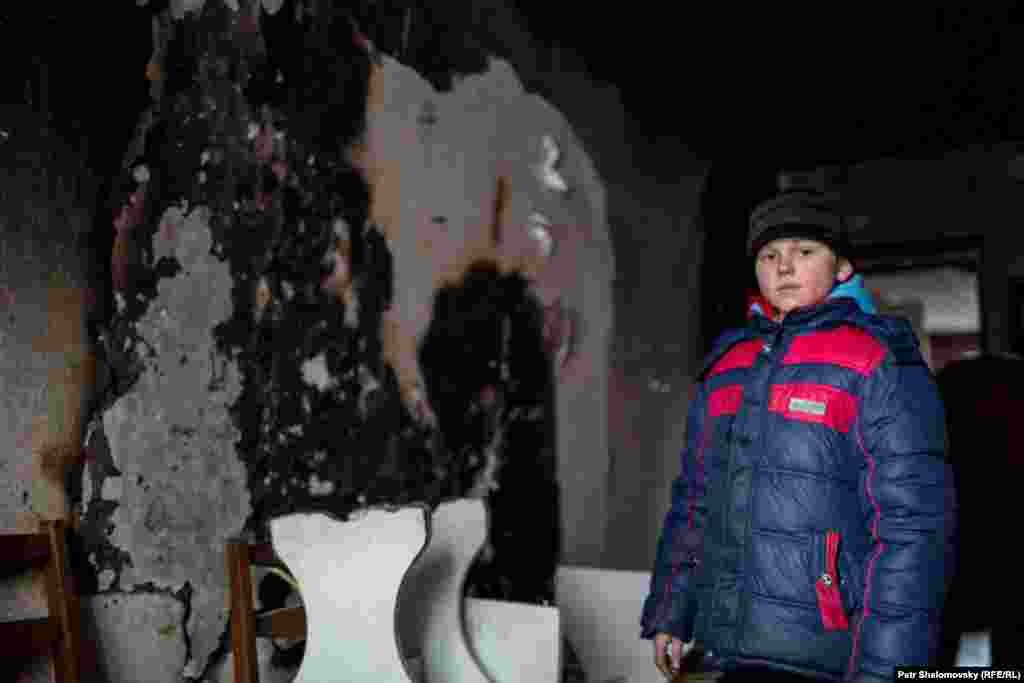 A boy stands in the ruins of his apartment building.