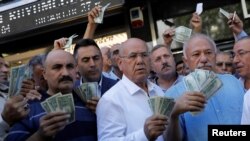 Istanbul workers hold up U.S. dollars outside of a currency exchange office. For Turkmen labor migrants, the dollar is the only major currency possible to transfer to Turkmenistan from abroad. (file photo)