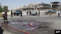 An Afghan firefighter clears the street of blood and debris at the site of a suicide car-bomb attack in Lashkar Gah on August 28.