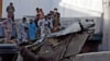 People stand next to the debris of a plane after crashed in a residential area near an airport in the southern seaport city of Karachi on May 22.