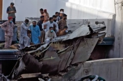 Karachi residents stand next to the debris of a passenger plane after it crashed near the city's airport on May 22.