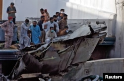 Karachi residents stand next to the debris of a passenger plane after it crashed near the city's airport on May 22.