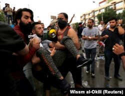 Demonstrators carry a man affected by tear gas during a protest over corruption, lack of jobs, and poor services, in Baghdad, Iraq October 25, 2019