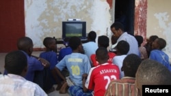 People sit around a television set to watch the opening game of the 2010 World Cup in Mogadishu