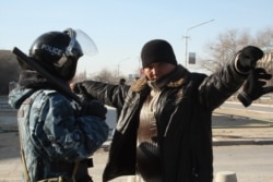 Сотрудник полиции проверяет мужчину в городе Жанаозен Мангистауской области, 19 декабря 2011 года.