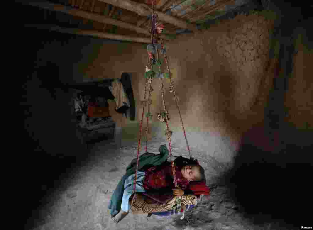 An internally displaced Afghan child sleeps in a hanging cot inside a shelter at a refugee camp in Kabul. Funding shortfalls have forced the World Food Program to cut rations for up to 1 million people in Afghanistan. (Reuters/Mohammad Ismail)
