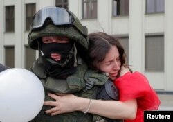 Një protestuese në Bjellorusi përqafon një pjesëtar trupave të Ministrisë së Brendshme.