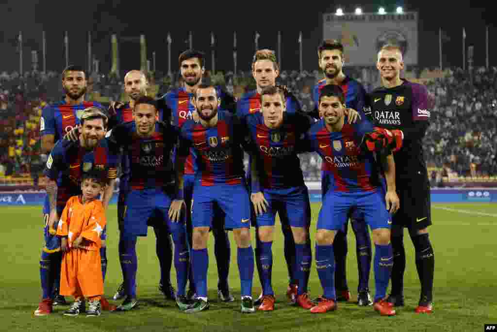 Afghan boy Murtaza Ahmadi poses for a picture with the FC Barcelona team on the pitch before the start of a friendly football match against Saudi Arabia's Al-Ahli FC in the Qatari capital, Doha. Murtaza became an online sensation after pictures of him wearing an improvised Lionel Messi jersey made from a discarded plastic bag went viral. He finally got to meet his idol (first row left) on December 13. The meeting was arranged by the organizing committee of the 2022 World Cup in Qatar. (AFP/Karim Jaafar)