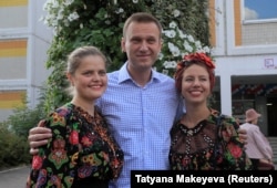 Two Russian women in traditional dress pose with opposition leader Aleksei Navalny, whom one analyst has described as "the best political animal in our political zoo." (file photo)