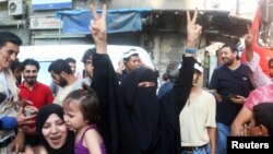 A Syrian woman flashes the victory sign as she celebrates the news of the breaking of the siege of rebel-held areas of Aleppo on August 6.