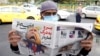 A man reads a copy of Iranian daily newspaper Sobhe Nou with a cartoon depicting U.S. President Donald Trump and a headline reading "Go to hell gambler" in Tehran on November 7.