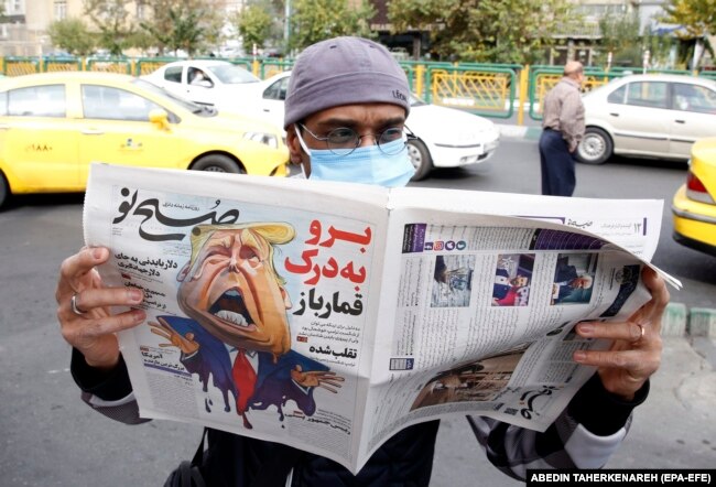 A man reads a copy of the Iranian daily Sobhe Nou in Tehran on November 7 that features a cartoon depicting U.S. President Donald Trump and a headline reading: "Go To Hell, Gambler."