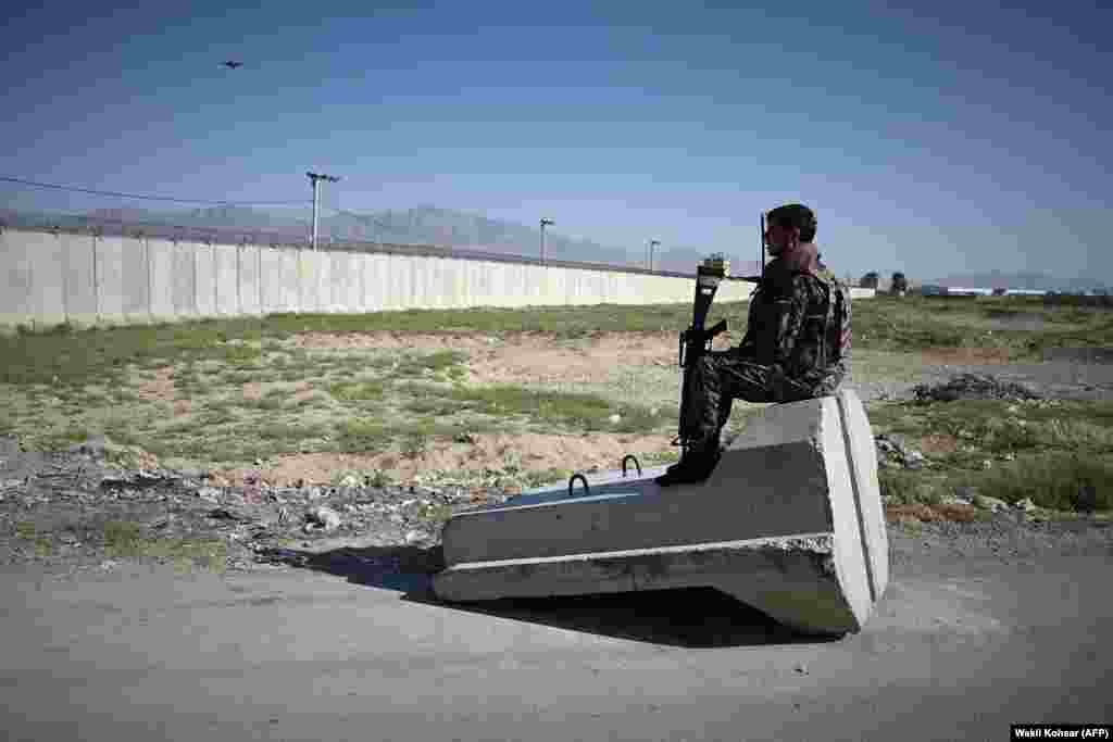 Një ushtar afgan qëndron i ulur pranë një pike të kontrollit afër bazës ushtarake në Bagram, që gjendet rreth 50 kilometra në veri të Kabulit.
