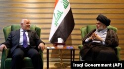 مقتدی صدر، روحانی شیعه (سمت راست) در دیدار با حیدر العبادی، نخست‌وزیر عراق
