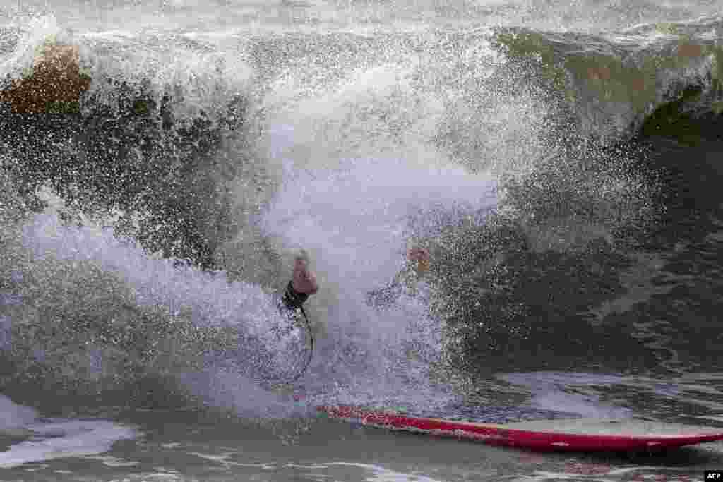 A surfer crashes off a wave at Charmouth, in Dorset, southern England after a major storm hit the region, forcing hundreds of thousands of evacuations and interrupting transportation. 