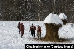 The workers stand next to well-chewed hay bales in the area where the bison's food is delivered.