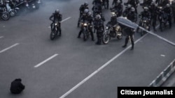 A lone protester sits with their head bowed in a standoff with security forces in Tehran during demonstrations over the country's struggling economy.