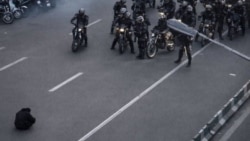 تصویری از یک معترض که مقابل موتورهای نیروهای ضدشورش نشسته است