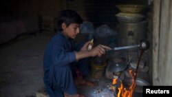 Kömür käninde işleýän pakistanly oglan işden soň çaý gaýnadynýar. Arhiw suraty