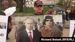 A protester holds up a photo of Vladimir Putin and Muammar Qaddafi in front of the White House on March 31, 2011.