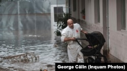 A man carries a baby stroller through floodwaters in the town of Slobozia Conach in Romania's Galati County on September 14.