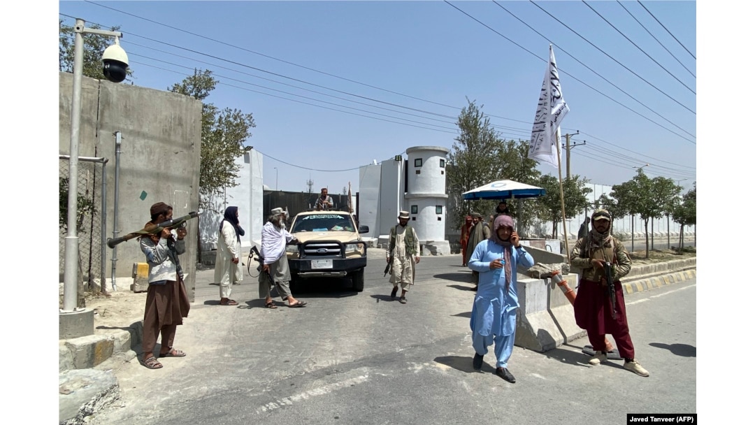 Taliban fighters stand guard at an entrance gate outside the Interior Ministry in Kabul on August 17. The armed militants are a common sight in the capital.