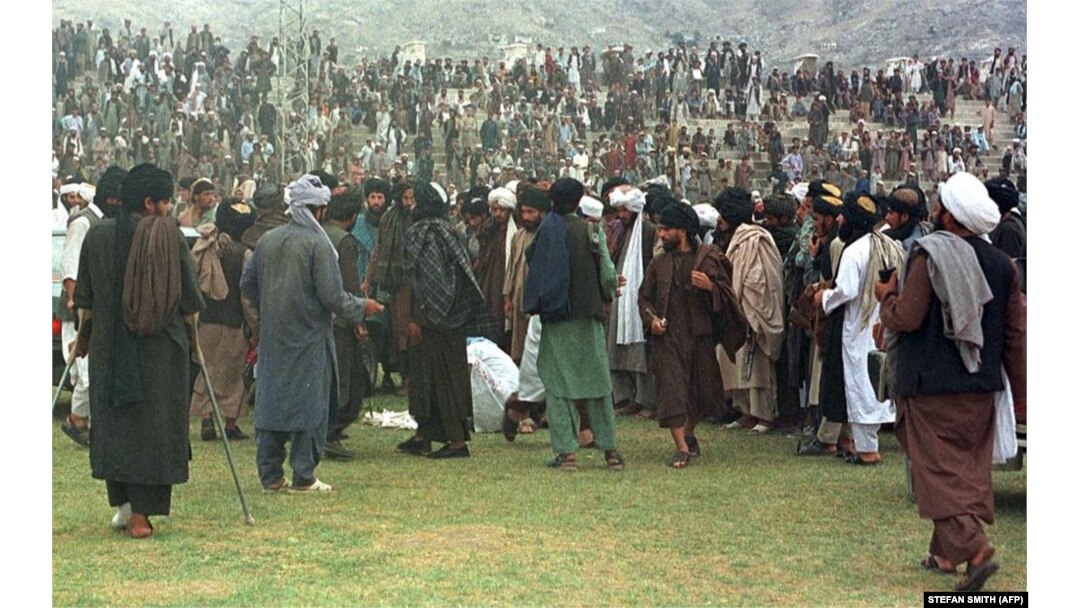 Taliban fighters gather around surgeons cutting off a thief's hand in Kabul's national stadium. (file photo August 1998)