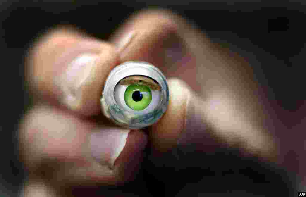 A worker holds a spare doll&#39;s eye at a workshop in Duesseldorf, Germany. (AFP/Martin Gerten)