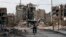 A man drives his motorbike past damaged buildings in Harasta, east of the Syrian capital, Damascus, on February 10.