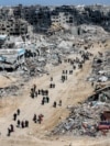 People walk past rubble of collapsed buildings near a destroyed clinic of the United Nations Relief and Works Agency for Palestine Refugees (UNRWA) at the Jabalia camp for Palestinian refugees in the northern Gaza Strip on January 19, 2025 after a ceasefi