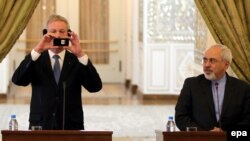 Swedish Foreign Minister Carl Bildt takes souvenir photos with his mobile phone at a press conference with Iranian Foreign Minister Mohammad Javad Zarif in Tehran on February 4.