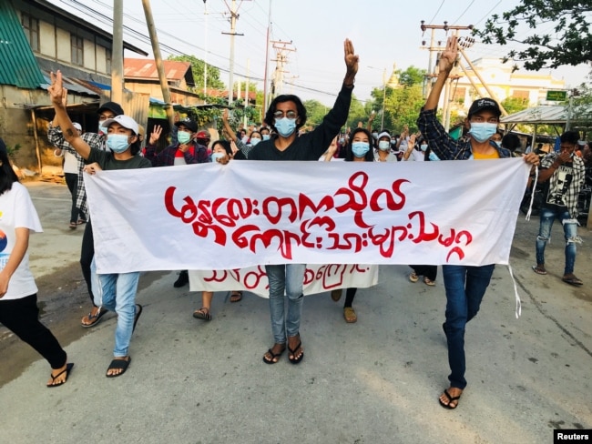 Студенти тримають банер і салютують трьома пальцями під час протесту проти хунти в М'янмі. 10 травня, 2021 року