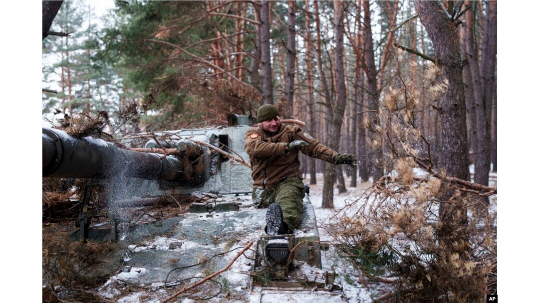 A disabled soldier with Ukraine's 127th Brigade who lost a leg in combat in 2015 takes the camouflage off his self-propelled howitzer on February 10.