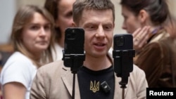 Народний депутат Олексій Гончаренко тримає смартфони, ведучи пряму трансляцію засідання українського парламенту в Києві, Україна, 8 січня 2025 року