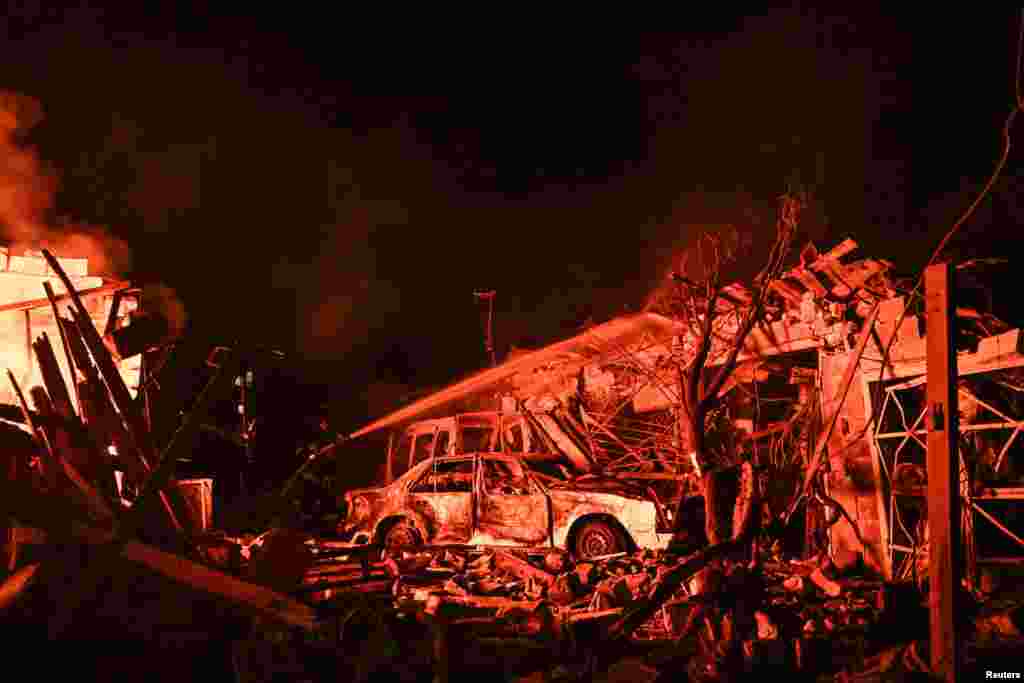 A firefighter (center left) works under the light of a burning building after strikes on Zaporizhzhya on August 11.A missile and drone attack on the city included a strike on a metalworking plant that killed seven people. Ukrainian President Volodymyr Zelenskiy claimed Russia used North Korean ballistic missiles in the Zaporizhzhya strikes.