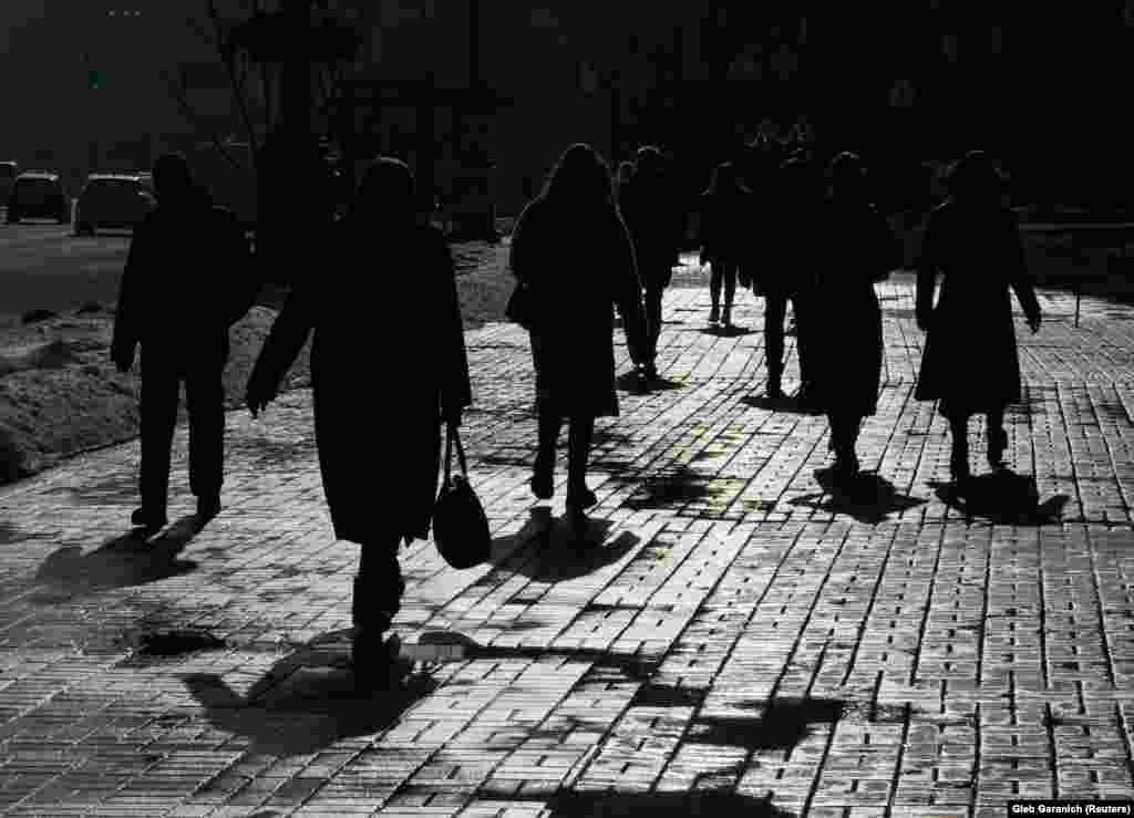 Pedestrians are silhouetted as they walk on the street during a sunny day in central Kyiv. (Reuters/Gleb Garanich)