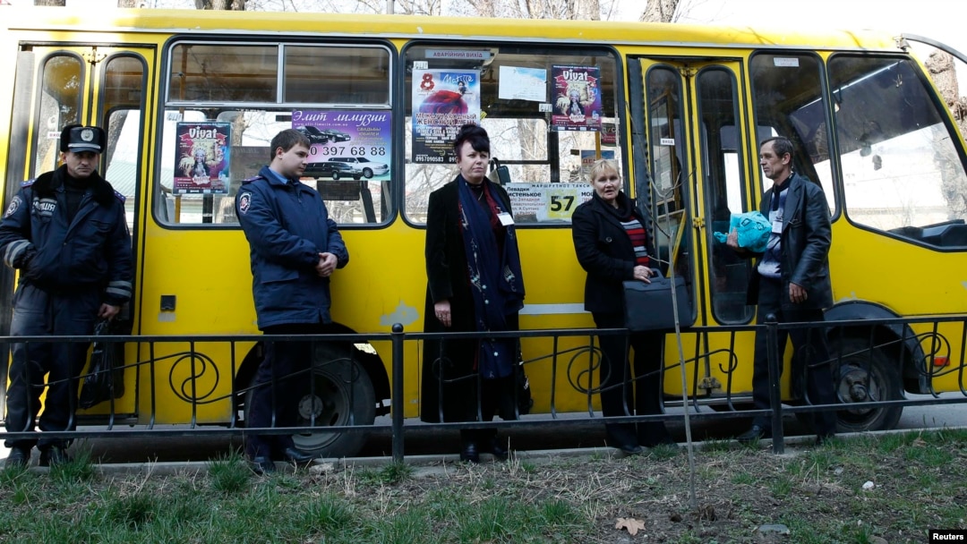 Election commission officials accompanied by the police wait for a bus to deliver ballots for the upcoming referendum in the Crimean capital Simferopol. 