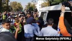 Билікке қарсы бейбіт митингіде полиция қатысушылардың бірін ұстап, көлікке салған сәтті түсіріп жатқан журналистер. Алматы, 21 қыркүйек 2019 жыл.