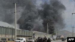 Afghanistan - Afghan policemen and security personnel watch as smoke rises from a guesthouse at the site of a suicide attack in Kabul, 02May2012