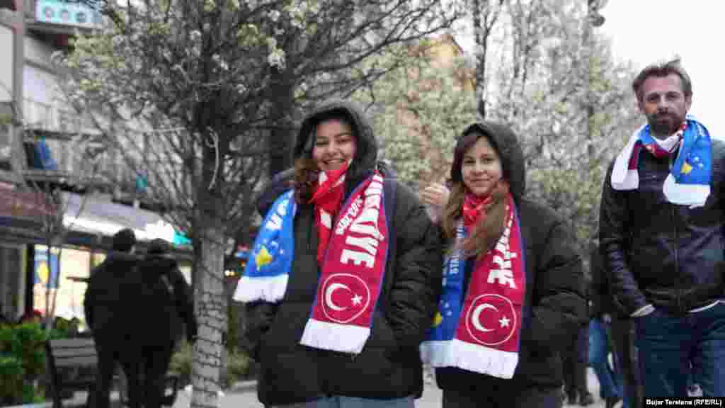 Një burrë dhe dy gra me shalle mbi supe të cilat mbajnë si emrin e Kosovës, ashtu edhe atë të Turqisë, pak para ndeshjes vendimtare mes Kosovës dhe Turqisë për një vend në Kupën e Botës 2026, të martën në Stadiumin "Fadil Vokrri".