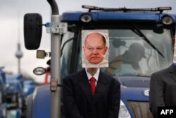 Traktor i maska sa likom njemačkog kancelara Olafa Scholza tokom protesta poljoprivrednika i vozača kamiona u Berlinu, Njemačka, 15. januara 2024.