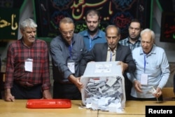 An electoral staff member empties a ballot box at a polling station on July 6 after voting ended in Iran's runoff presidential election. Pezeshkian's victory came amid a turnout of 49.8 percent, considerably higher than the record-low 40 percent in the first round of the election.