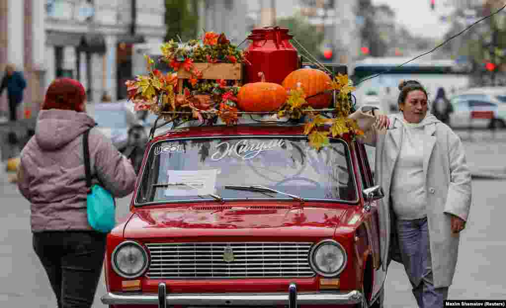 A woman poses with a retro VAZ 2101 car during the annual BRICS summit in Kazan, Russia.