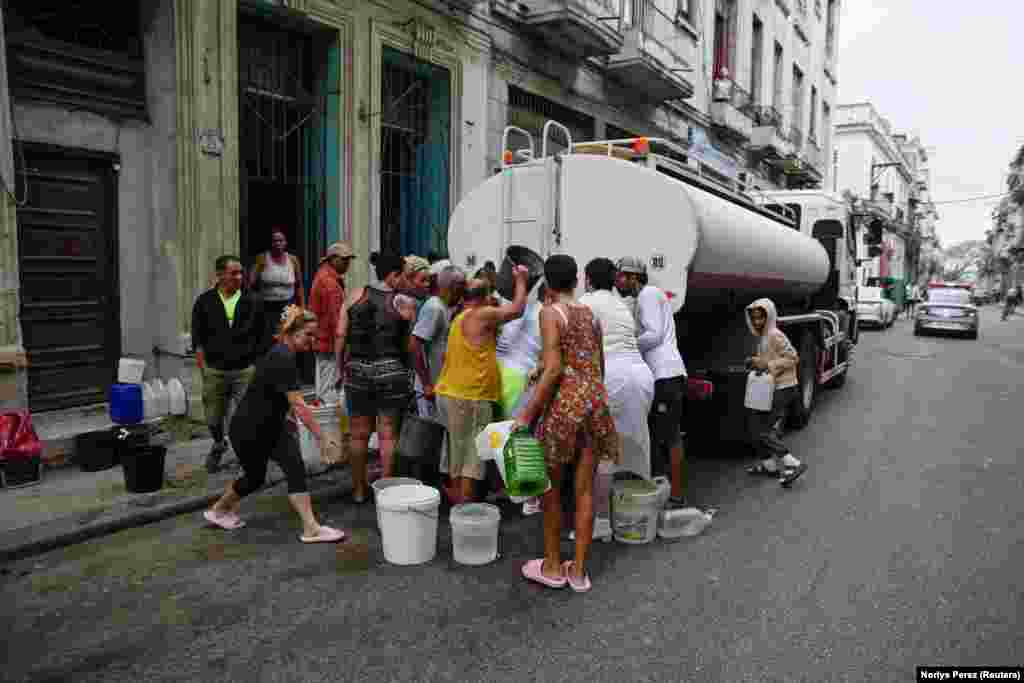 People fill up water containers from a truck in Havana, Cuba, on March 19 after severe fuel shortages disrupted water-pumping facilities in the country.