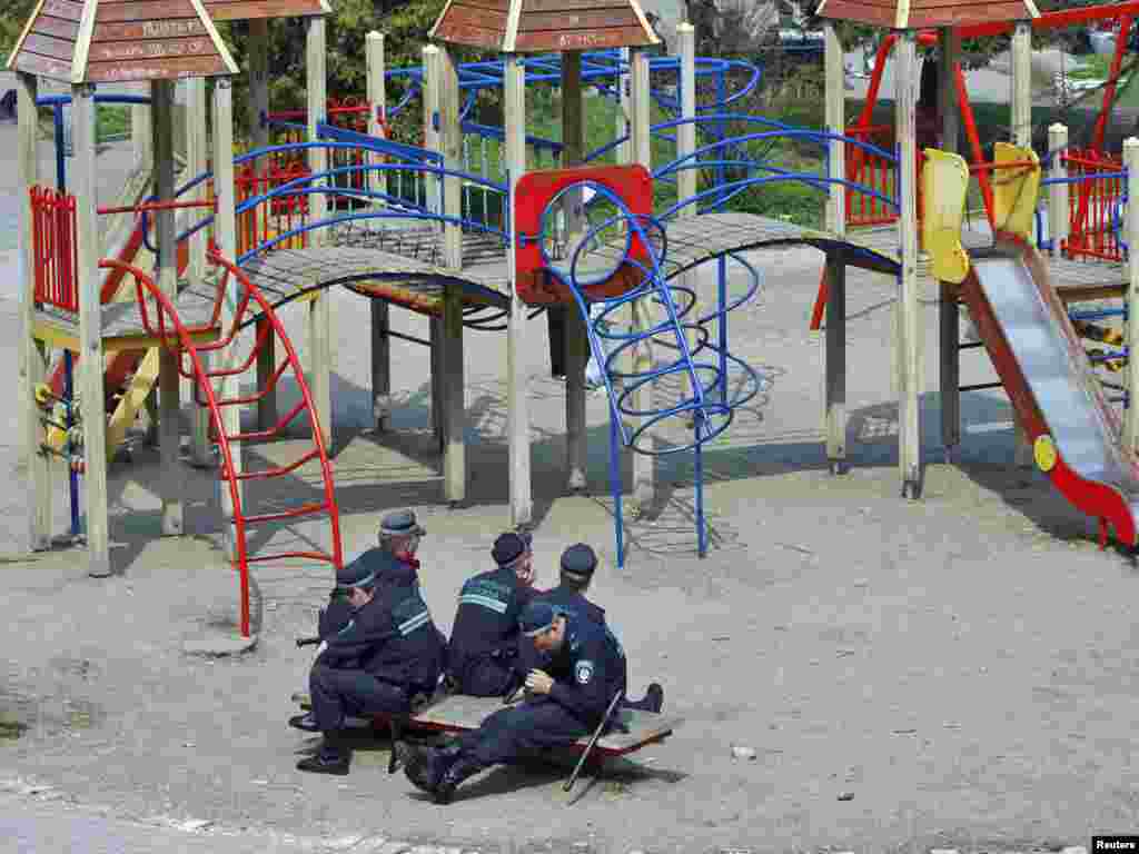 Ukrajina - Dječije igralište bilo je zgodno mjesto za odmor ovim policajcima, Akijev, 27.04.2011. Foto: Reuters / Gleb Garanich