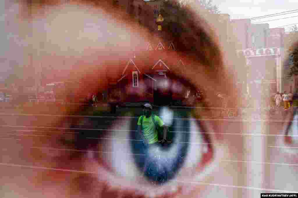 A food courier is reflected in a covering of a social advertisement poster while crossing a street with his bicycle in Moscow. (AFP/Kirill Kudryavtsev)