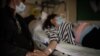 Egy férfi fogja terhes felesége kezét a Covid-járvány idején egy párizsi kórházban 2020. november 17-én