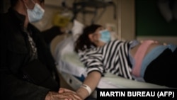 Egy férfi fogja terhes felesége kezét a Covid-járvány idején egy párizsi kórházban 2020. november 17-én