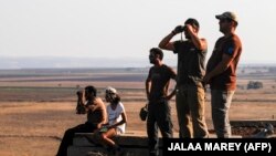 A picture taken on July 23, 2018 from the Israeli-annexed Golan Heights shows Israelis looking out across the border watching as warplanes backing a Syrian-government offensive carry out air strikes in the southwestern Syrian province of Daraa.